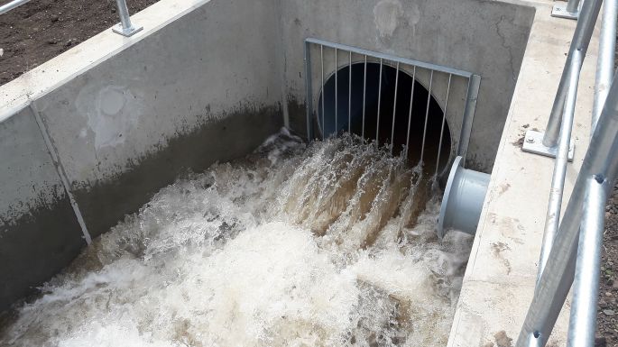 Tosender Wasserauslauf in einen Fluss mit eisernen Strahlbrechern am Rohrende