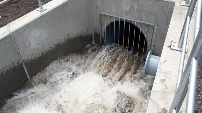 Tosender Wasserauslauf in einen Fluss mit eisernen Strahlbrechern am Rohrende